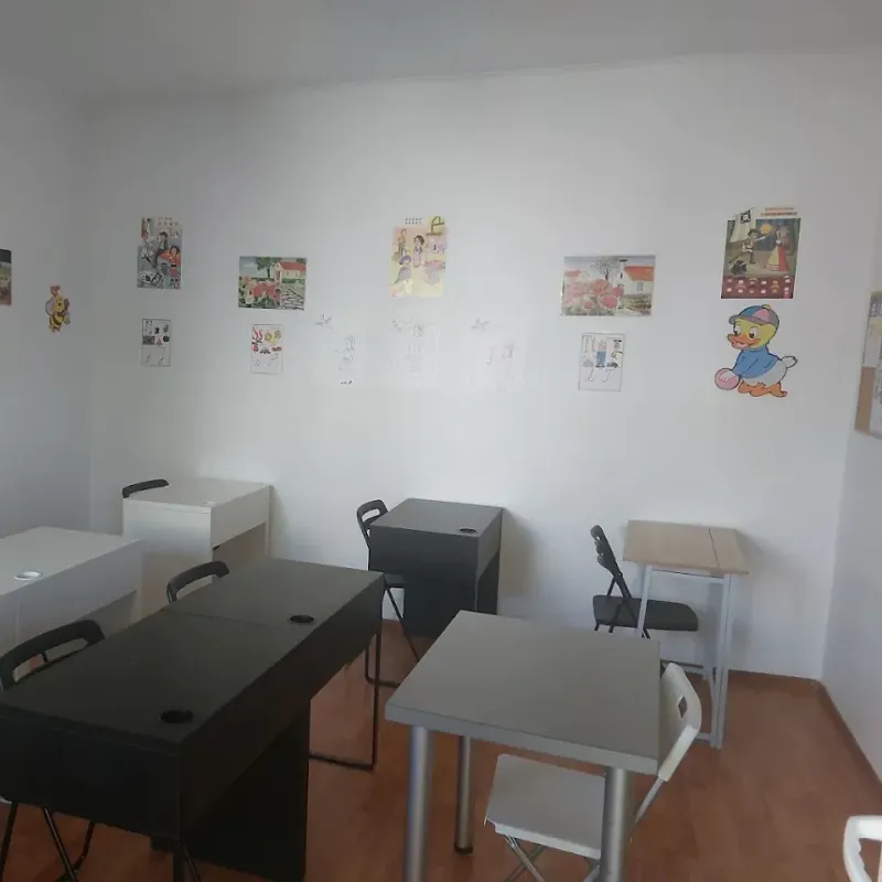 Sală de curs cu planșe cu literele alfabetului și desene ale copiilor pe perete